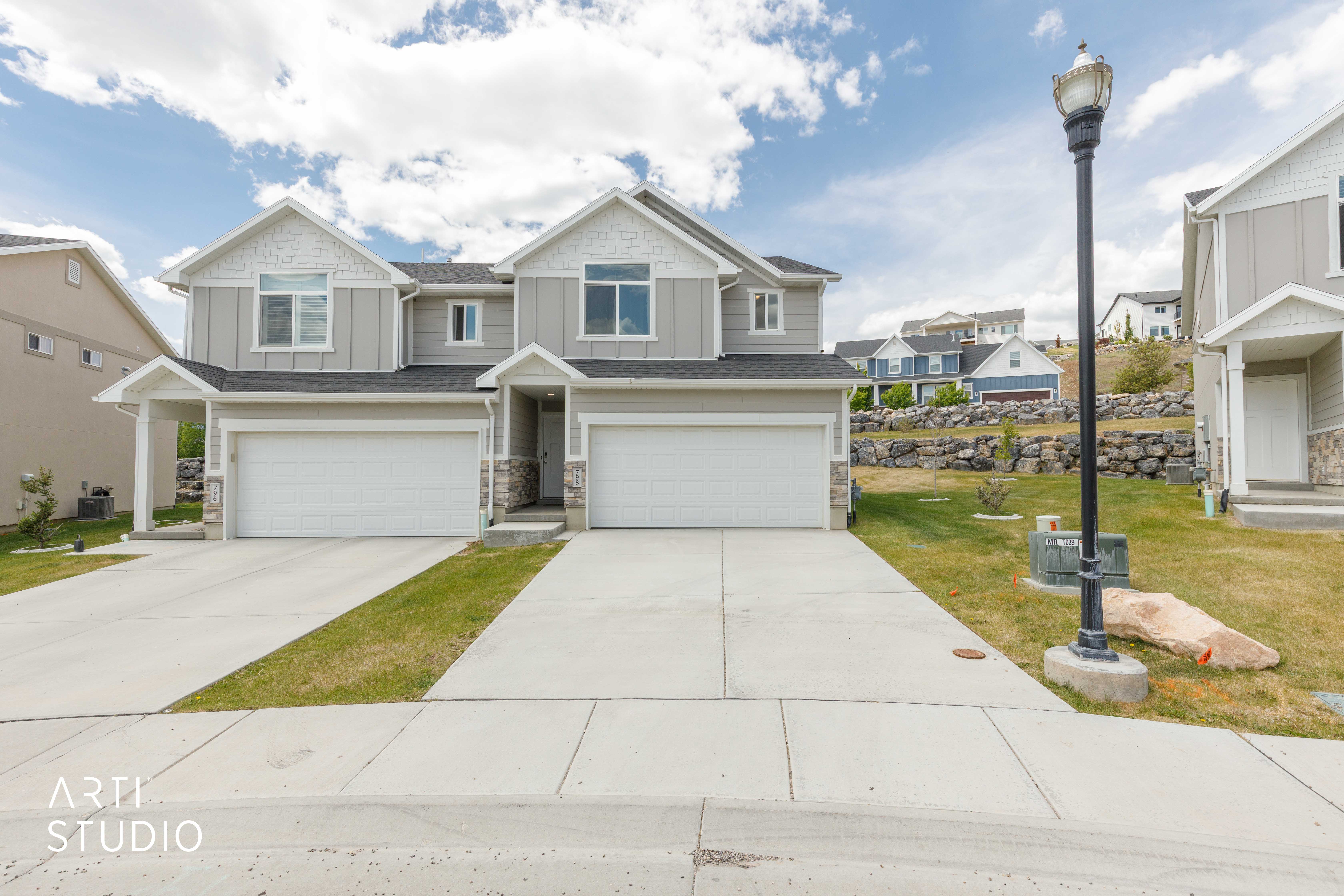Modern duplex exterior featuring light gray siding with white trim accents and dark roofing
