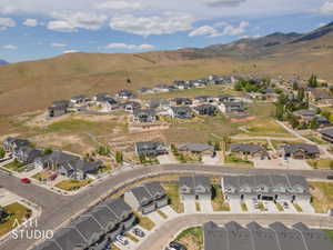 Expansive residential community featuring a mix of single-family homes and townhomes, set against a backdrop of natural hills and distant mountains