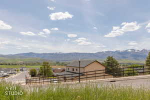 Residential property featuring light-colored siding, a dark roof, and a black horizontal slat fence