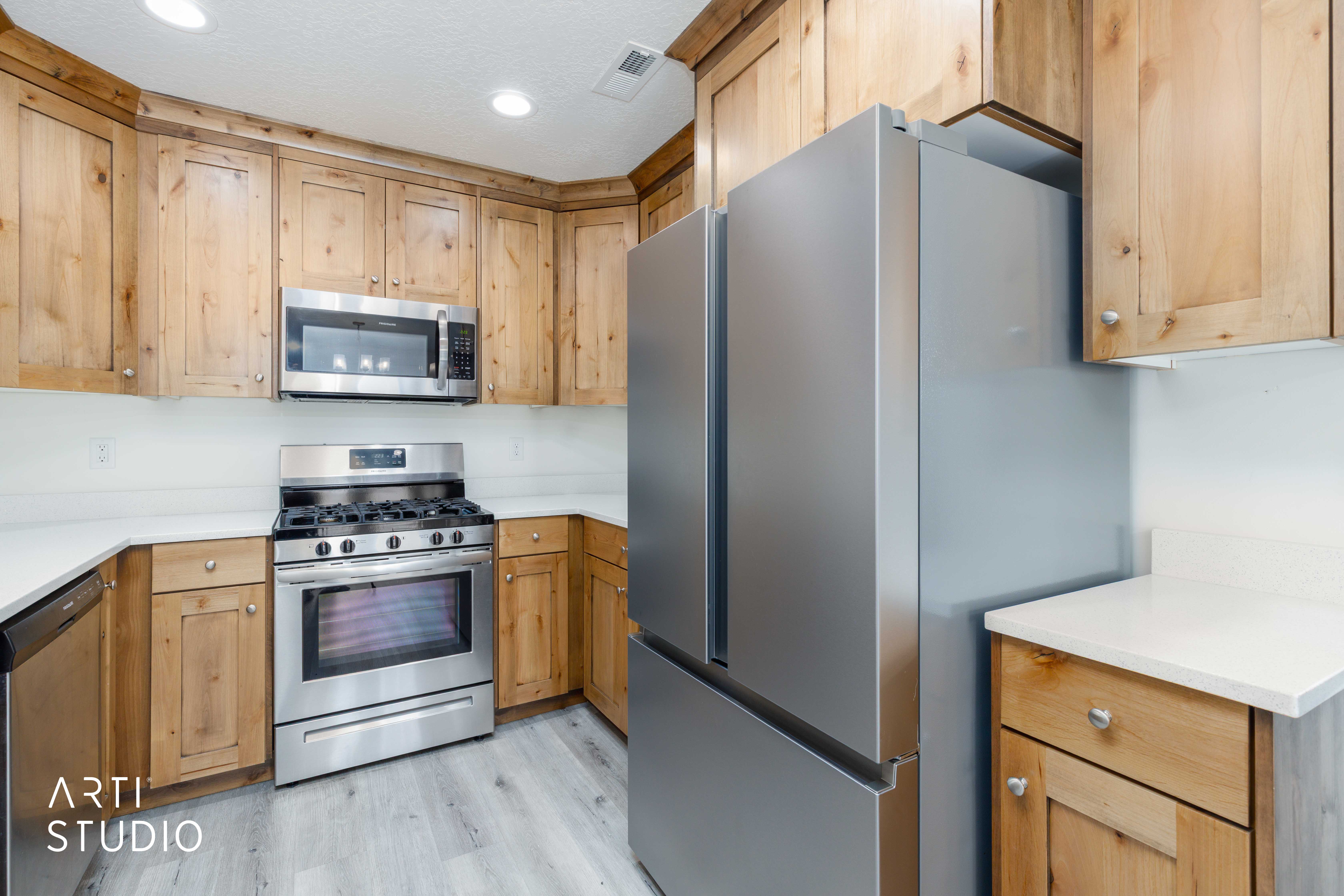 Kitchen featuring light wood-finish cabinetry, stainless steel appliances, a gas range with an oven, and light-toned countertops