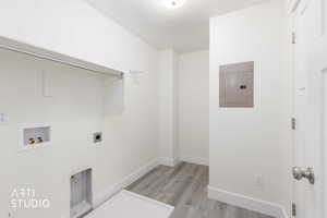 Dedicated laundry space featuring wood-finish flooring, white walls, and a built-in hanging rod