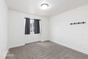 Neutral interior space featuring light-toned walls, textured carpeting, and a flush-mount ceiling light