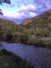 River frontage featuring clear waters, natural rock formations, and abundant mature trees
