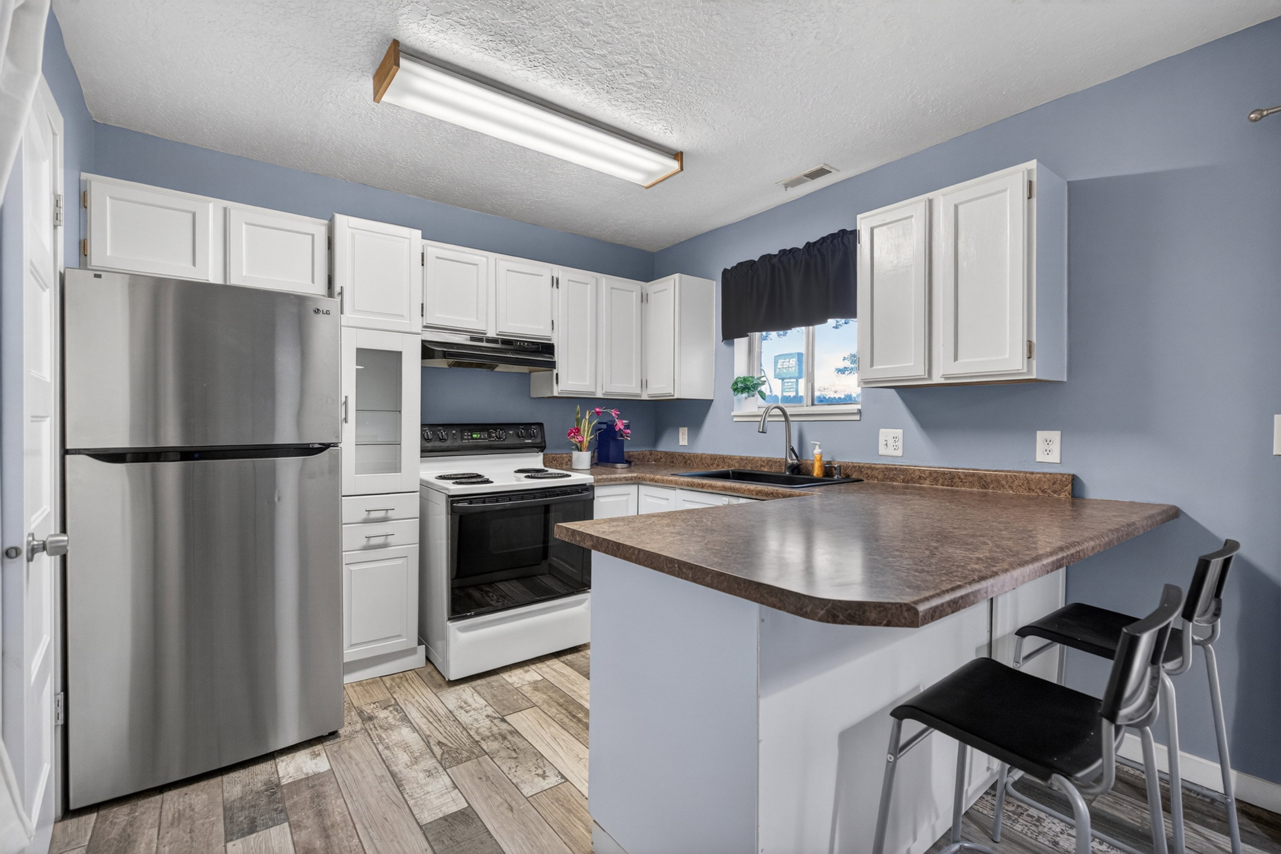 Kitchen featuring white cabinetry, wood-finish flooring, and a breakfast bar