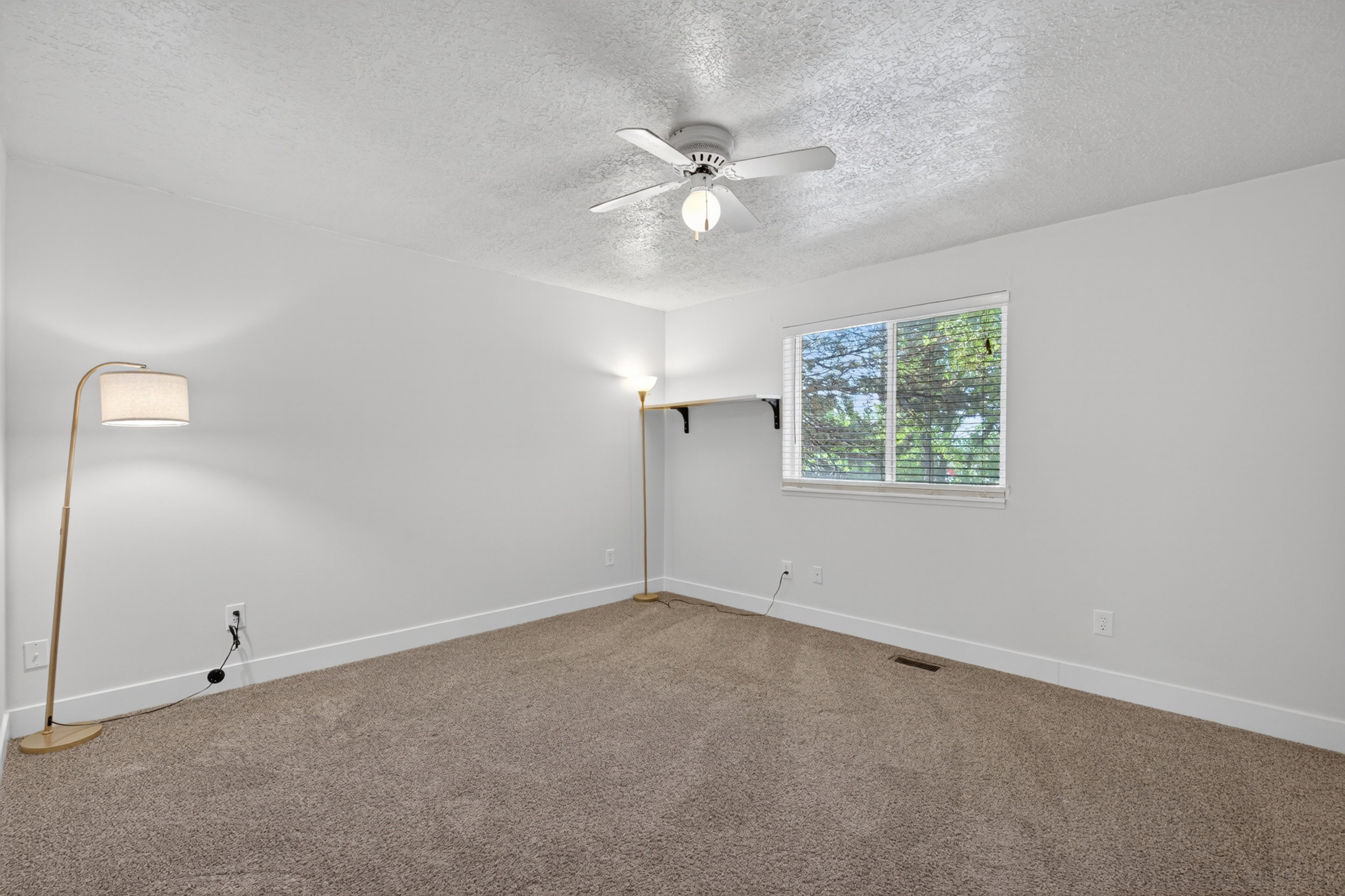 Carpeted room featuring a ceiling fan with integrated lighting, a window with horizontal blinds, and white baseboards