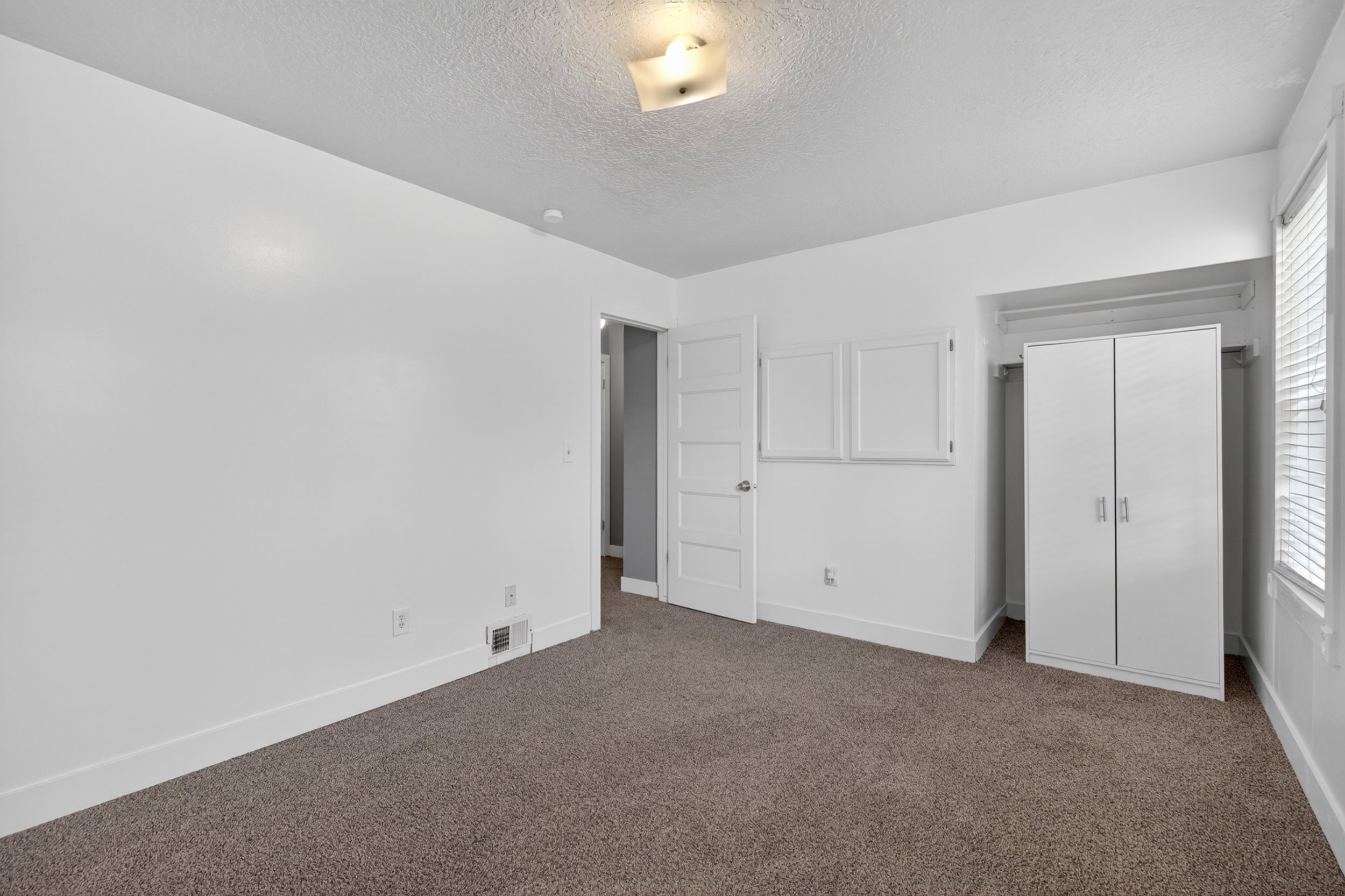 Neutral interior room with light-colored walls and textured carpeting