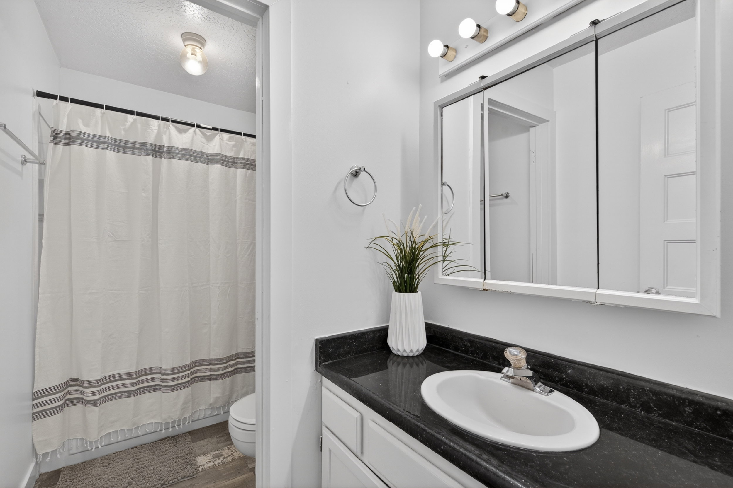 Bathroom featuring a white vanity with a dark countertop, an integrated sink, and a mirrored medicine cabinet