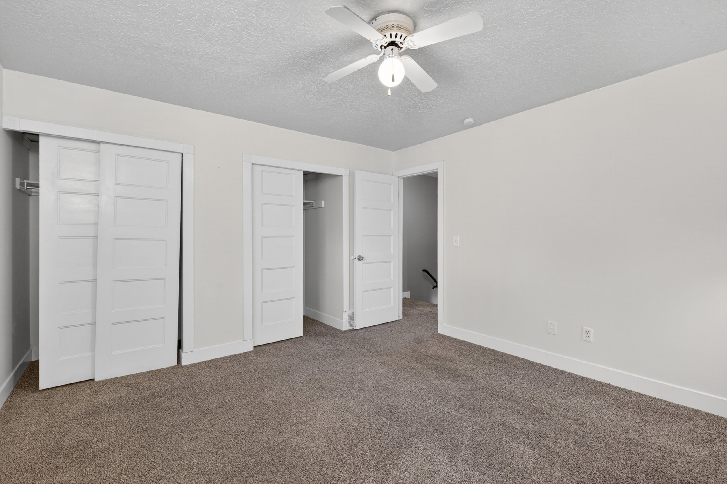 Room featuring neutral-toned carpet, light-colored walls, and a ceiling fan with integrated lighting