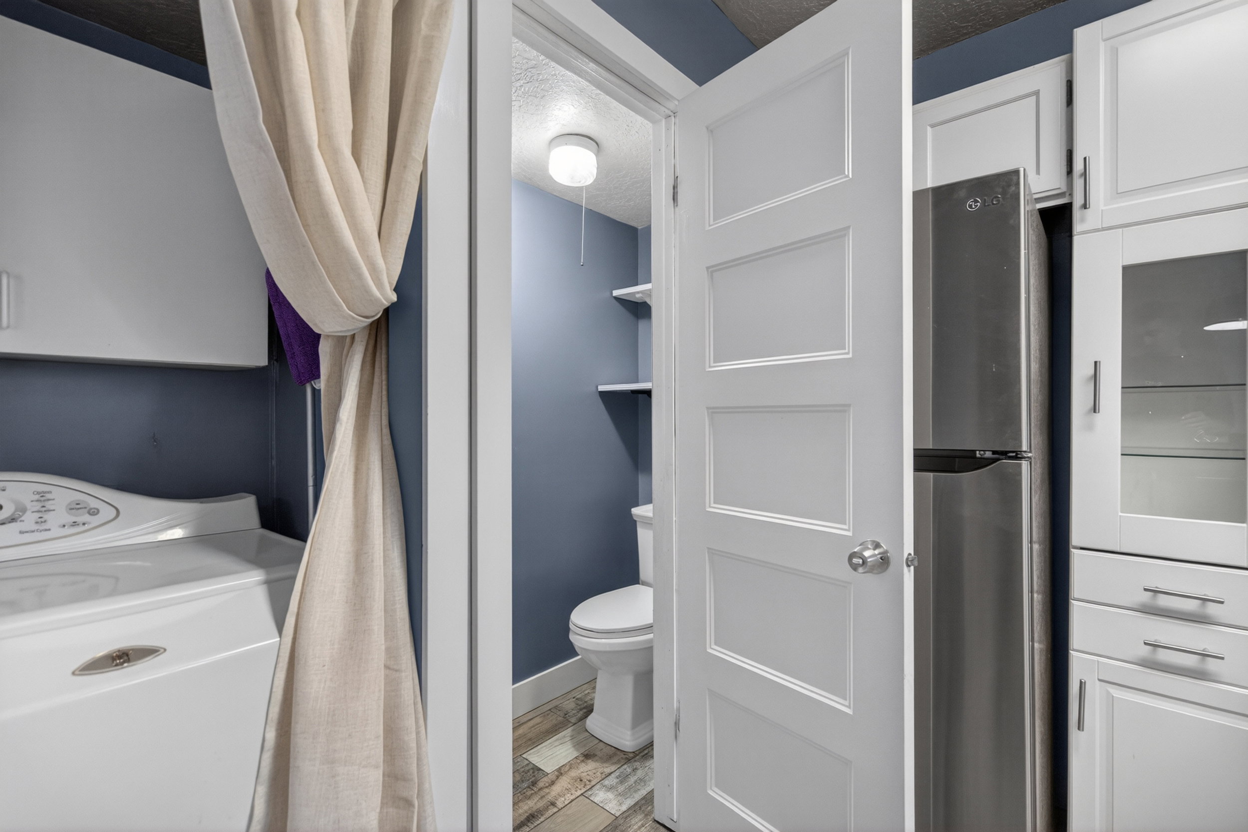 Integrated laundry area featuring a white top-load washing machine and white cabinetry