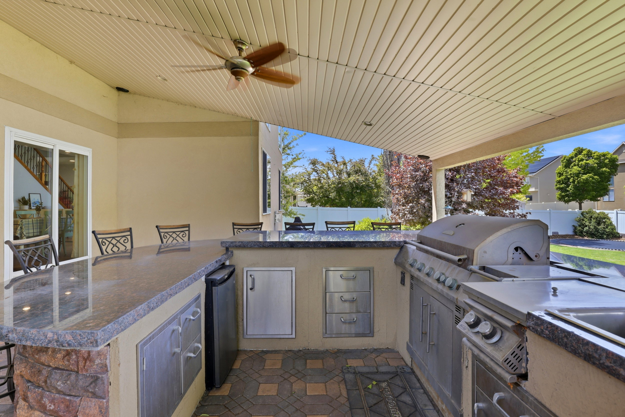 Outdoor kitchen featuring granite countertops, built-in stainless steel appliances, and a ceiling fan on a covered patio