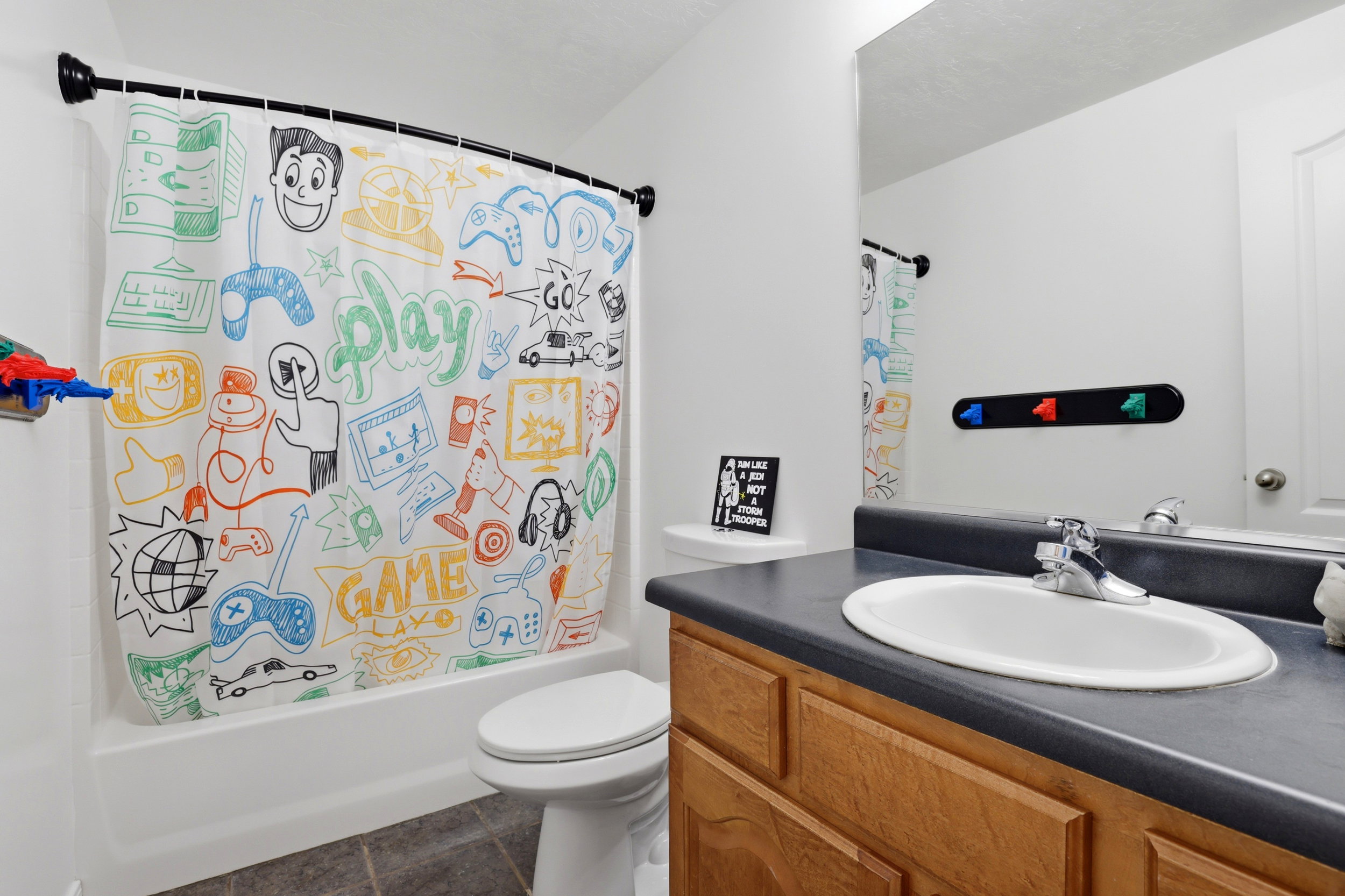 Bathroom featuring a built-in wood-finish vanity with a dark countertop and integrated sink, a large wall mirror, and a toilet