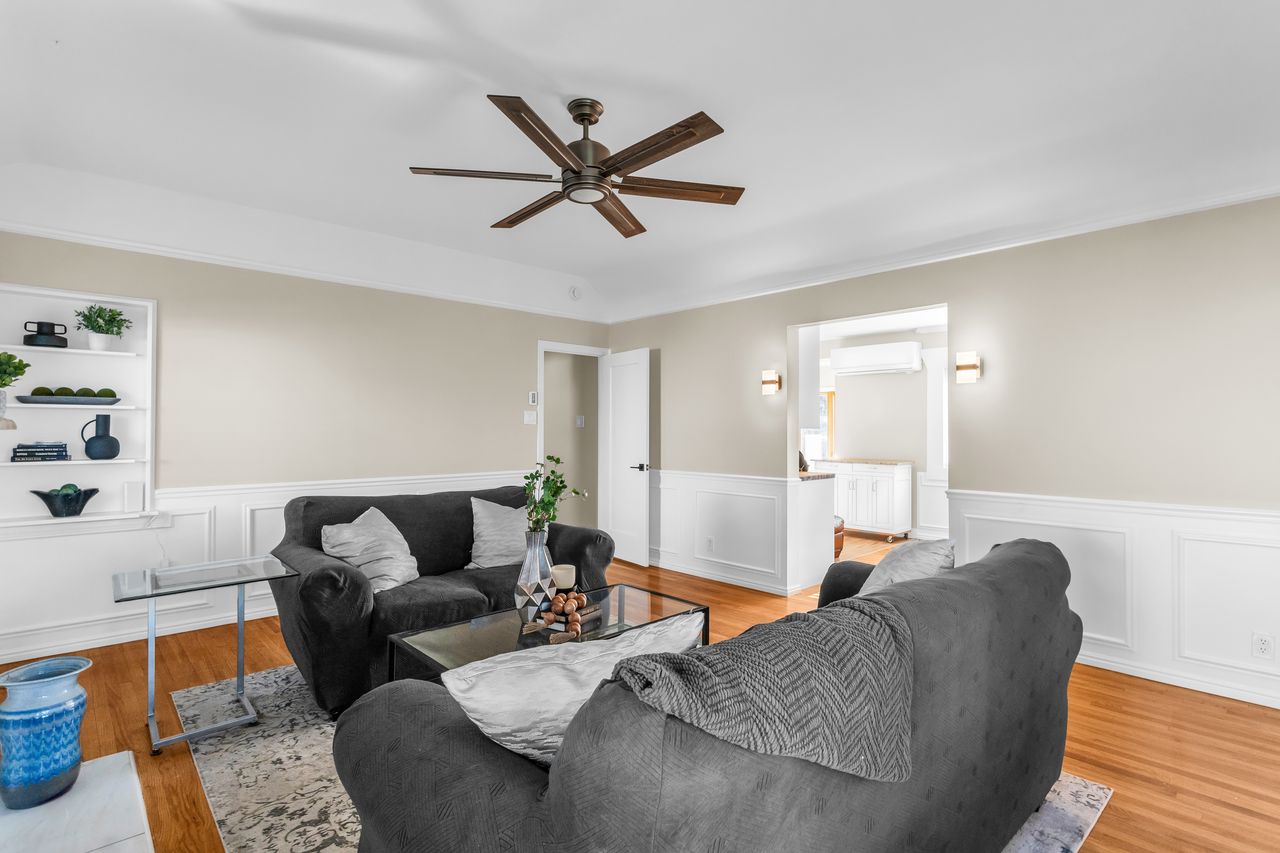 Living space featuring wood-finish flooring, white wainscoting, and recessed built-in shelving