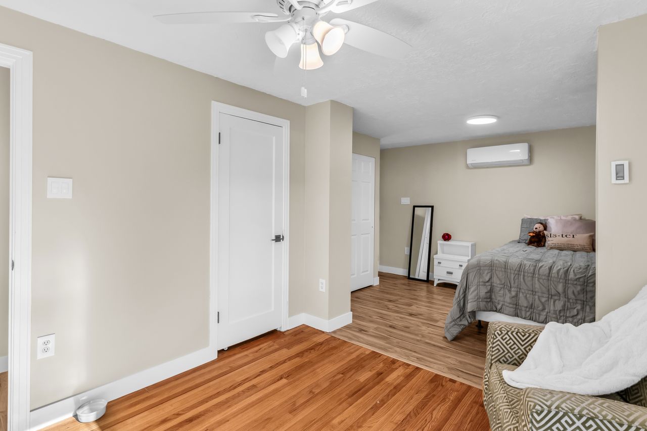 Interior space featuring wood flooring, neutral wall tones, white trim, and a ceiling fan with integrated lighting