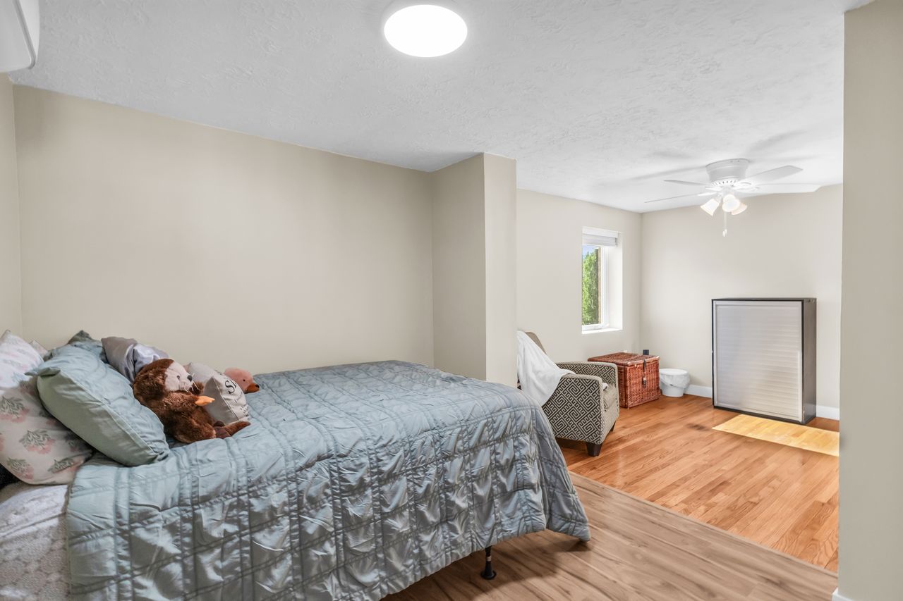 Spacious room featuring wood-finish flooring, a contemporary ceiling light fixture, and a ceiling fan
