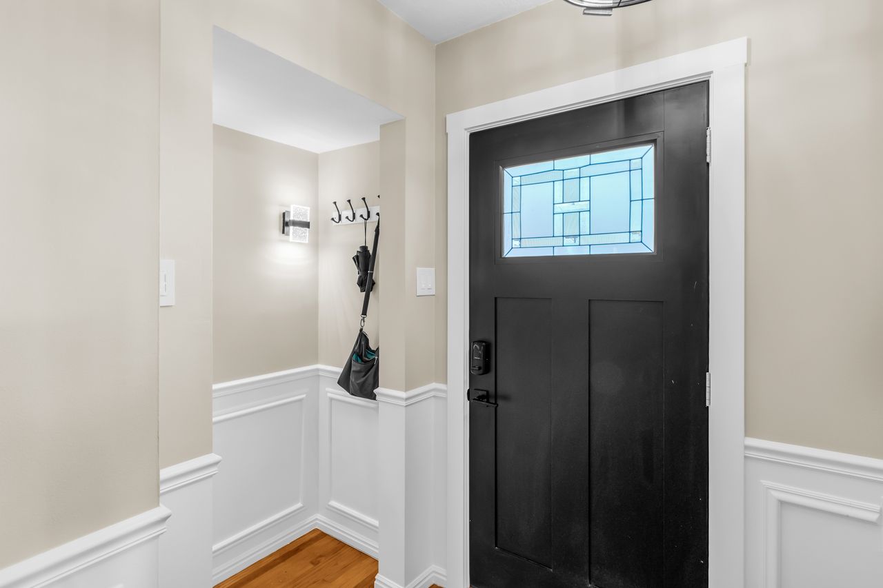 Entryway featuring a black paneled door with a decorative glass insert, white trim, and light beige wall paint