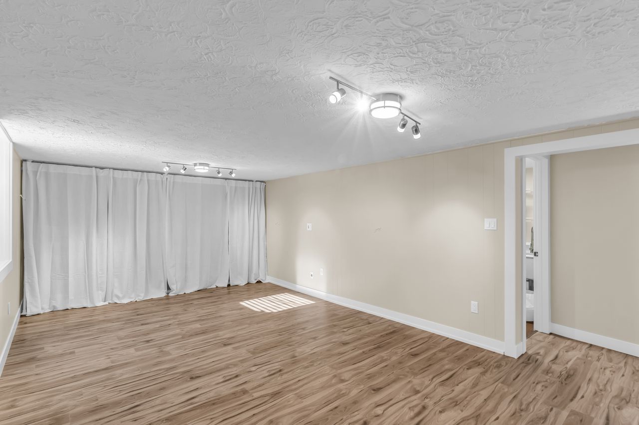 Spacious room featuring wood-finish flooring, light-toned walls, and recessed lighting