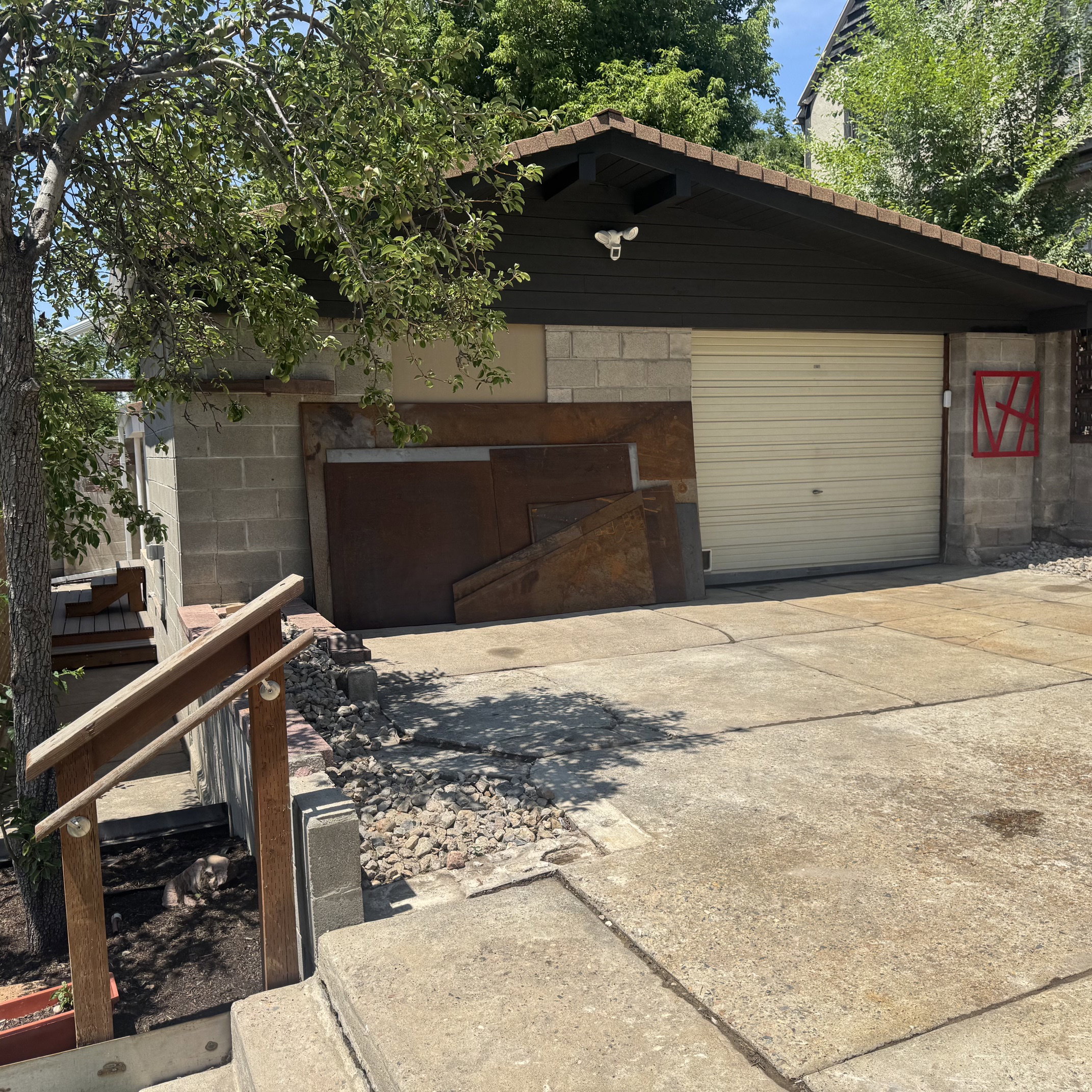Garage structure with a pitched roof featuring dark fascia and soffits, block wall construction, and a light-colored garage door