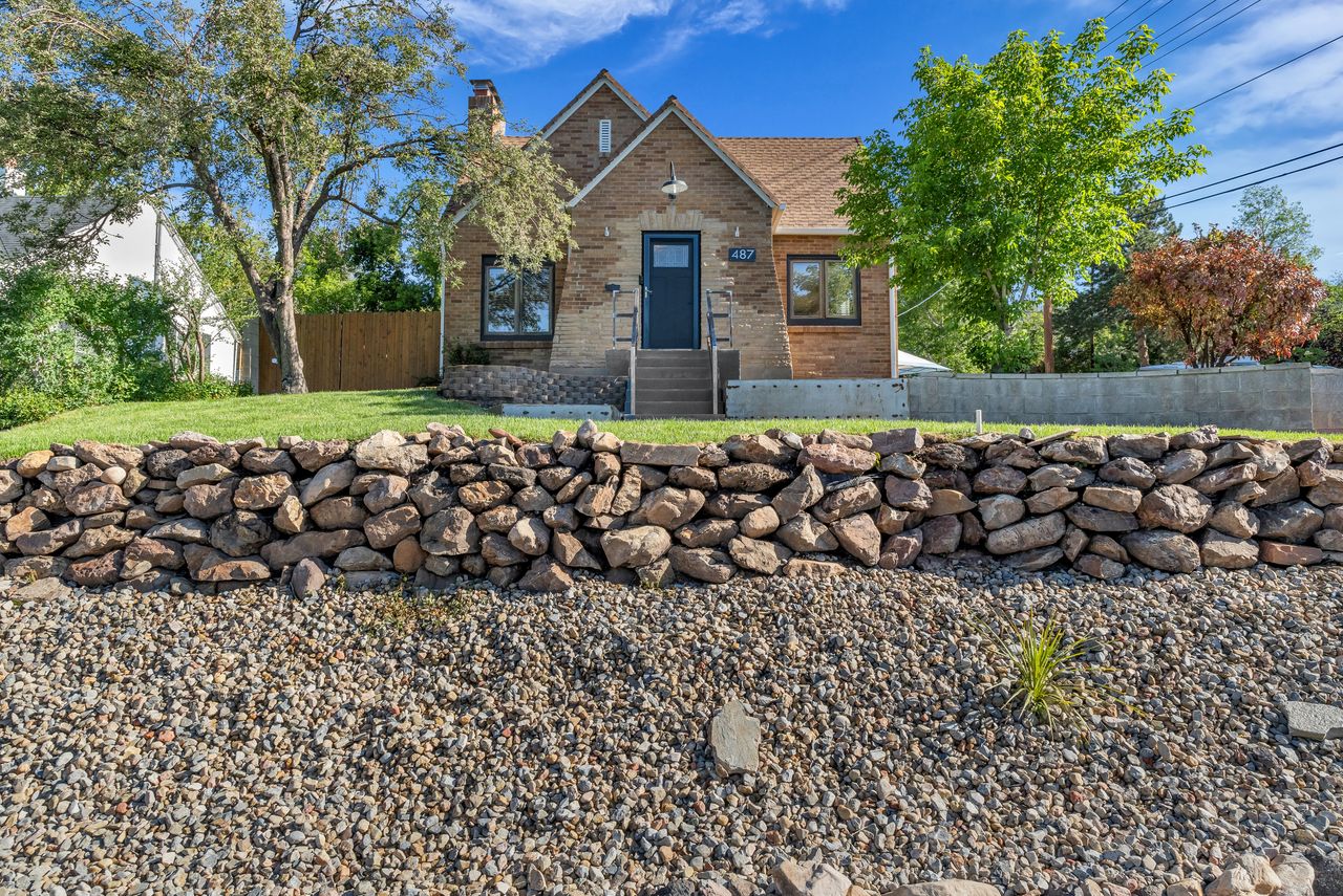 Brick exterior with a prominent stone retaining wall and a gravel-covered slope