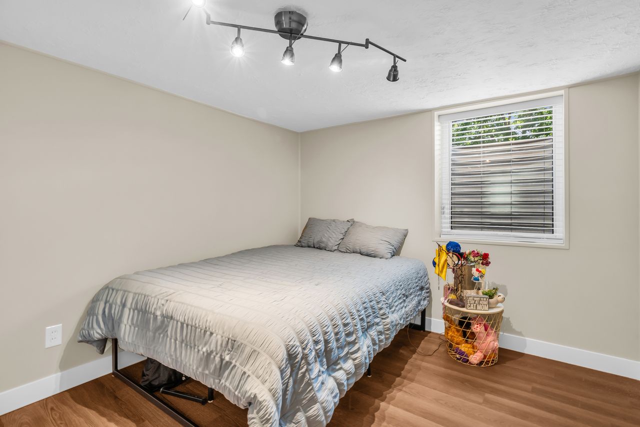Room featuring wood-finish flooring, a window with blinds, and light-toned walls