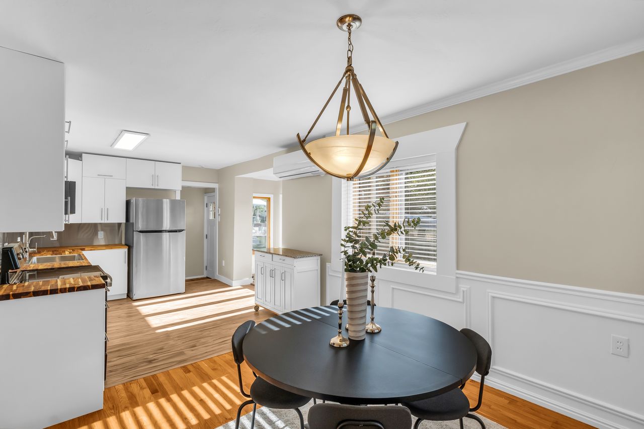 Dining area featuring a decorative chandelier, white wainscoting, and wood-finish flooring