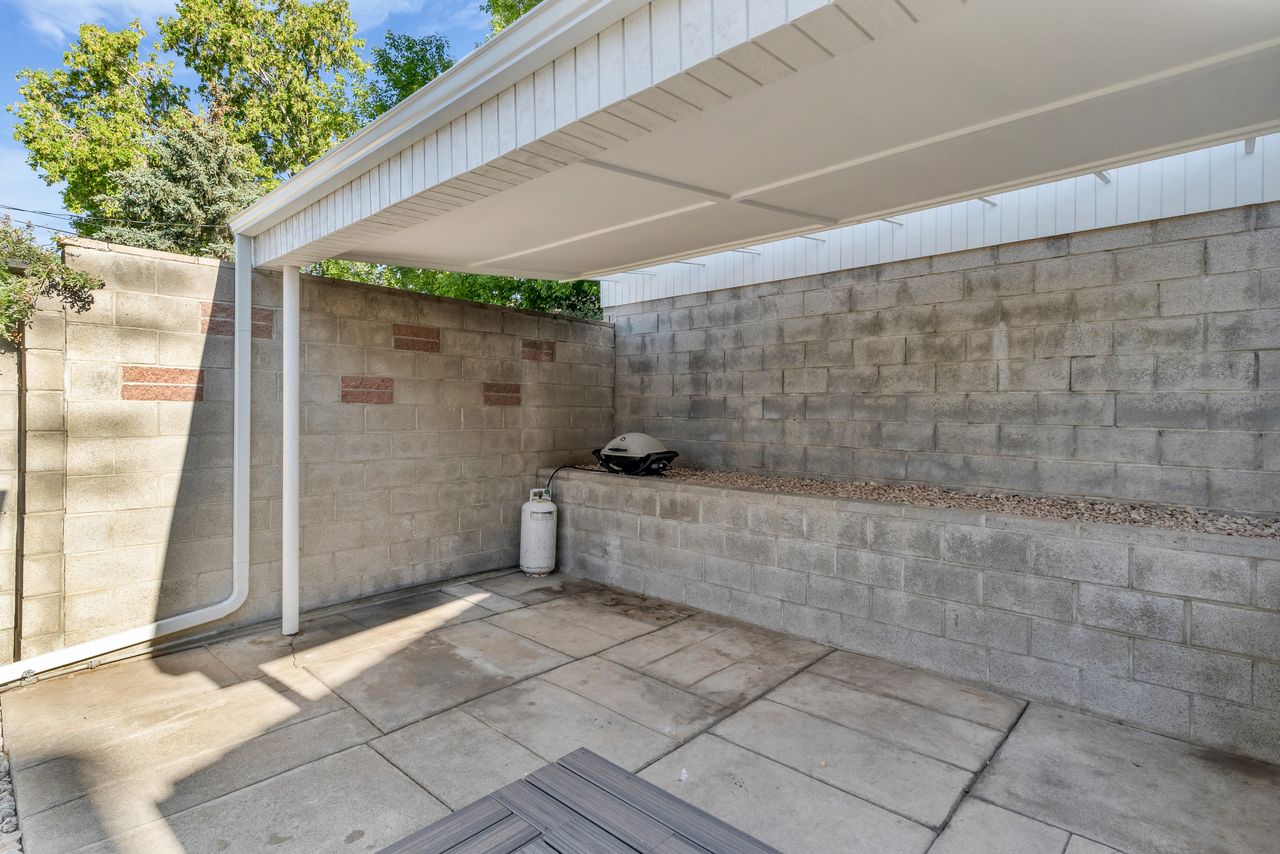 Covered patio area featuring a block wall surround with integrated planter and concrete paver flooring