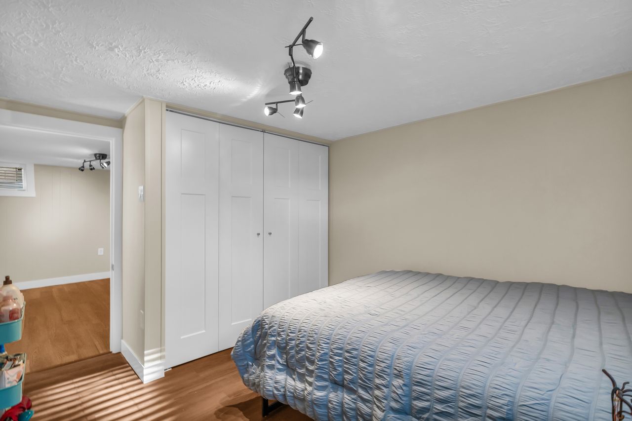 Bedroom featuring wood-finish flooring, track lighting, light-toned wall paint, and white bi-fold closet doors