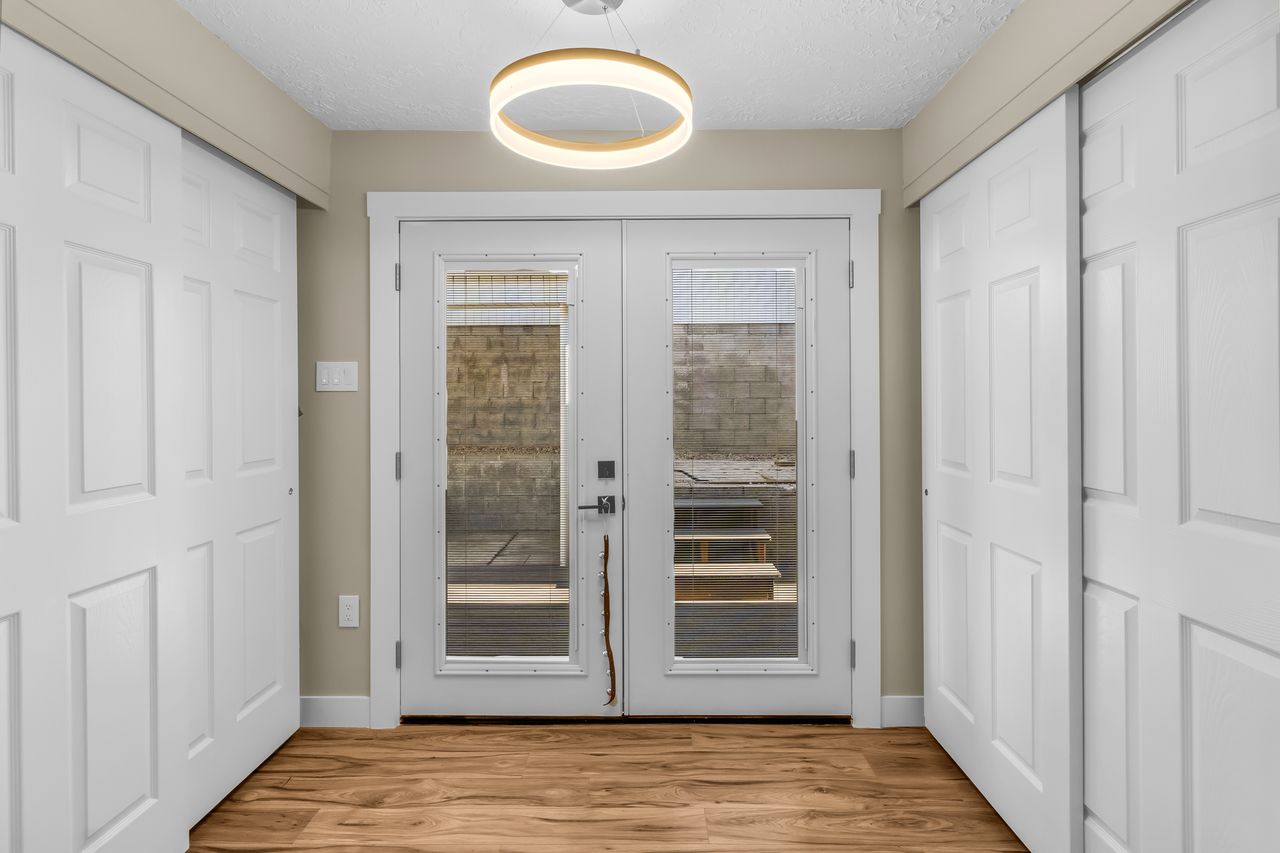 Wood-finish flooring with a modern ceiling light fixture and white trim