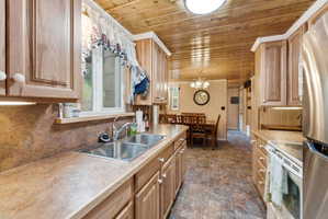 Kitchen featuring wood-finish cabinetry, a double basin stainless steel sink, and a laminate countertop