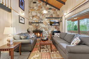 Vaulted wood-paneled ceilings with exposed beams complement the full-height stone fireplace