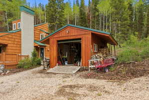 Detached garage with a roll-up door, side window, and covered wood storage area
