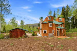 Multi-level exterior featuring cedar shake siding, a green metal roof, and a covered front porch