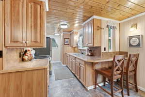 Kitchen featuring extensive wood cabinetry, laminate countertops, a built-in breakfast bar, recessed lighting, and resilient flooring