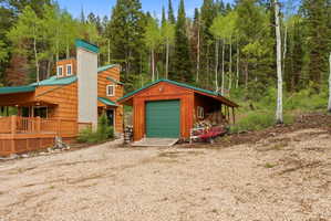Wood-shingle exterior with a green metal roof, featuring a multi-level deck and a prominent stone-clad chimney