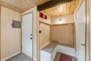 Entryway featuring light wood-finish paneling, a wood-finish plank ceiling, and built-in bench seating