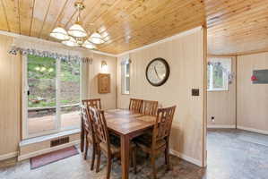 Dining area featuring wood-paneled walls and ceiling, a brass chandelier, and tile flooring
