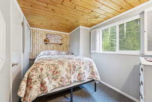 Bedroom featuring a wood-finish plank ceiling, paneled walls, and carpeted flooring