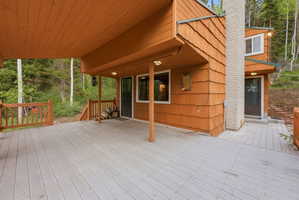 Expansive outdoor decking features a covered area, wood-finish railings, and integrated lighting