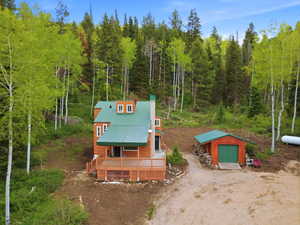Wood-sided residence featuring a green metal roof and a spacious front deck