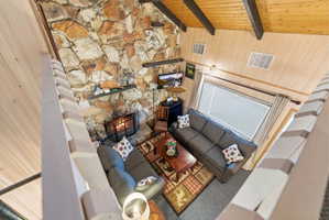 Vaulted wood-finish ceilings with exposed beams complement a floor-to-ceiling stone fireplace