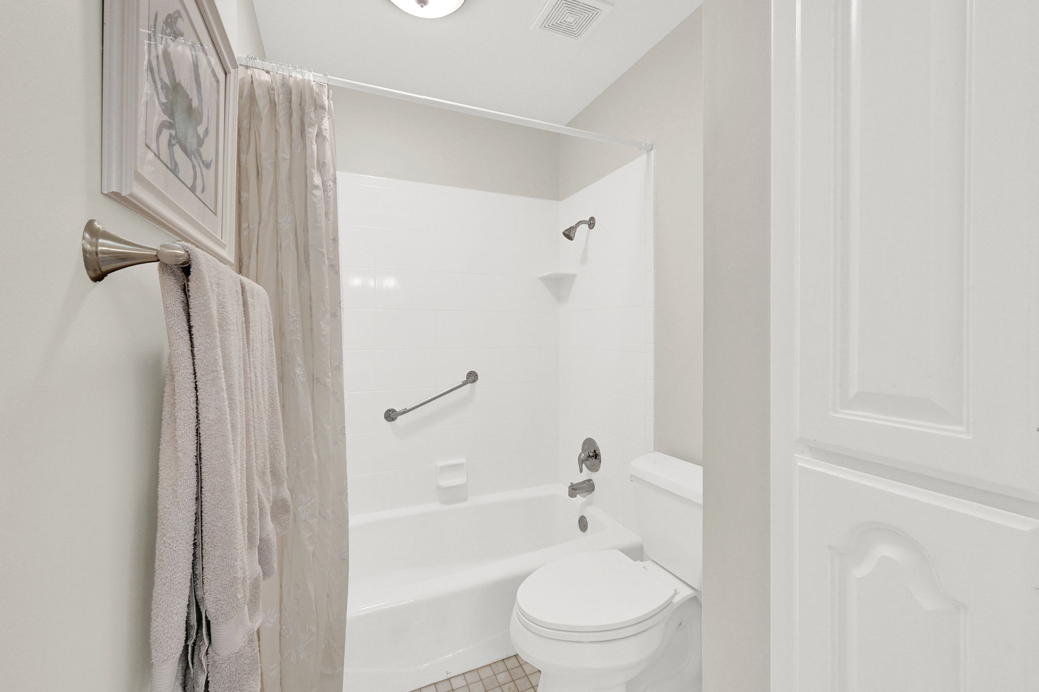 Full bathroom featuring a white tub/shower combination, brushed nickel fixtures, and a white toilet
