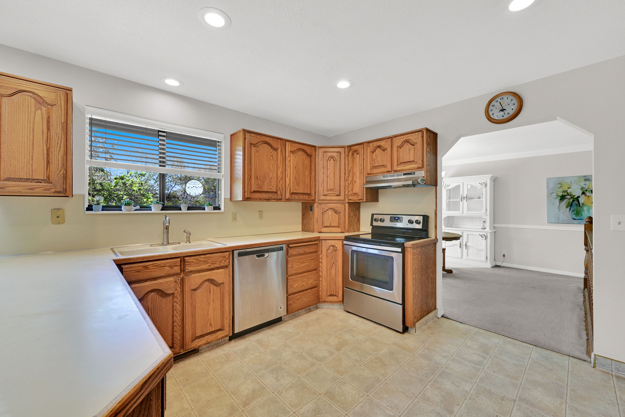 Kitchen featuring oak cabinetry, tile flooring, and stainless steel appliances, including a range and dishwasher