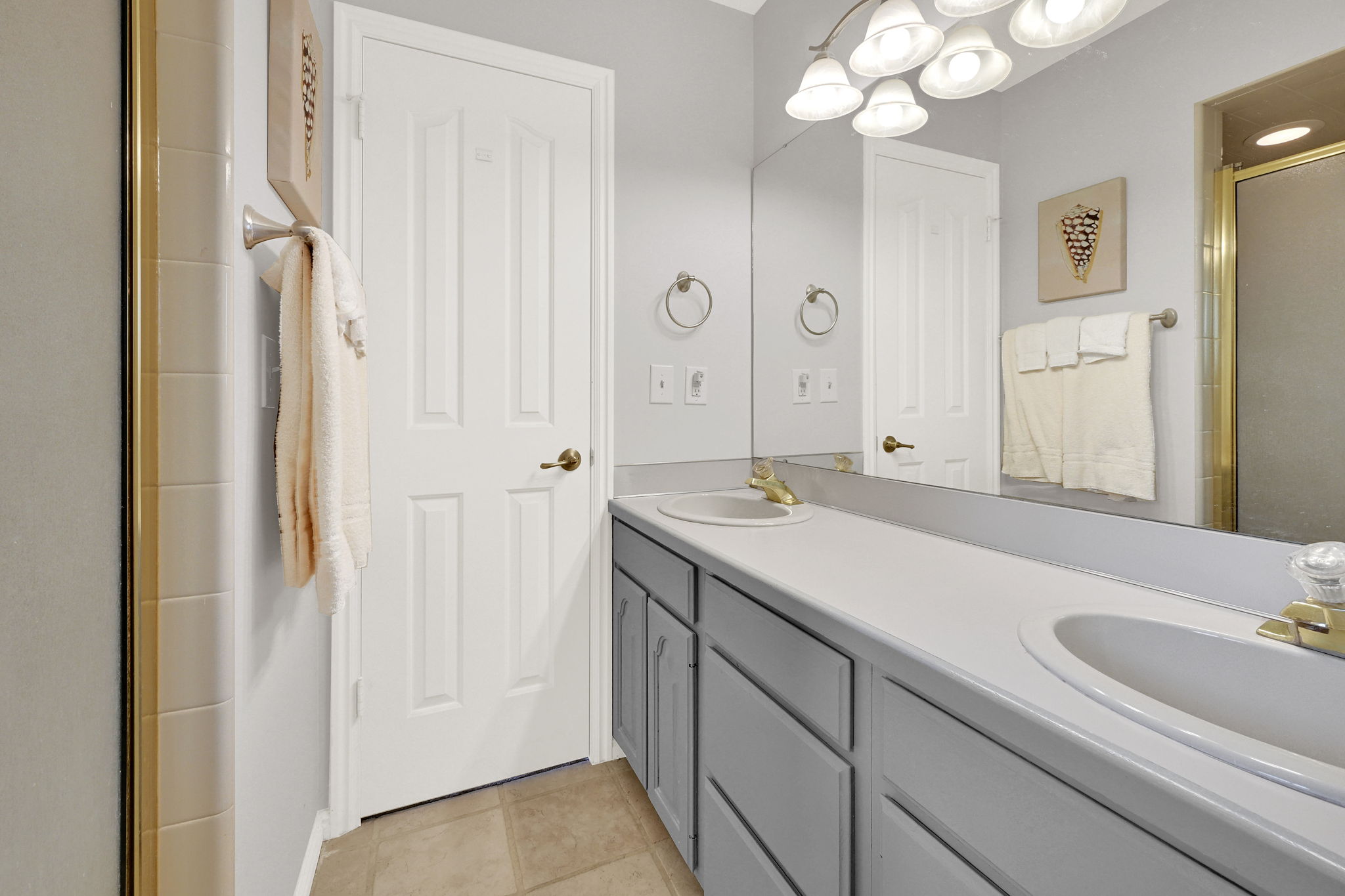 Primary bathroom with dual vanity with integrated sinks and gray cabinetry, expansive wall-mounted mirror, and tile flooring