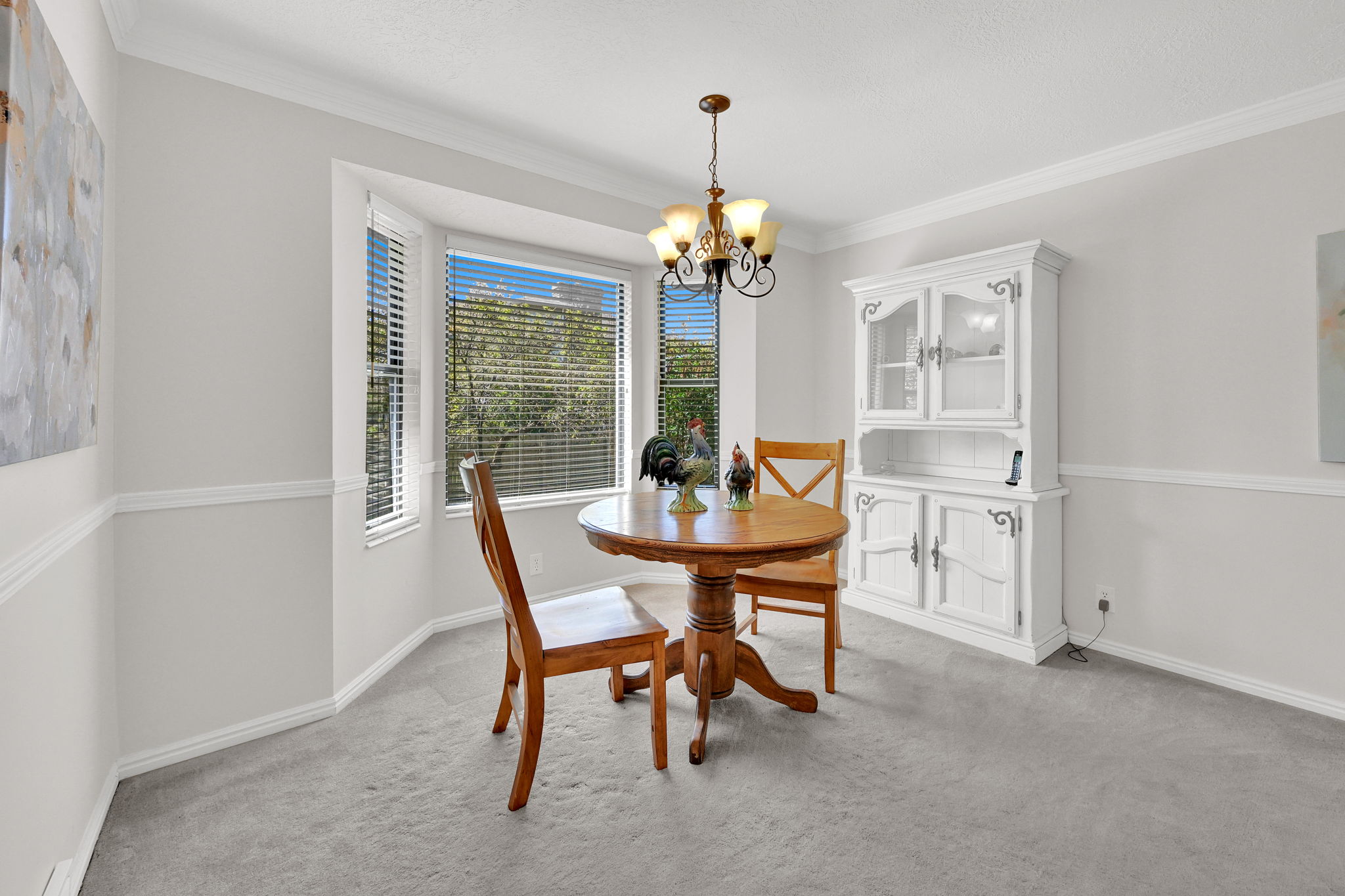 Bay window with horizontal blinds, featuring a chandelier light fixture