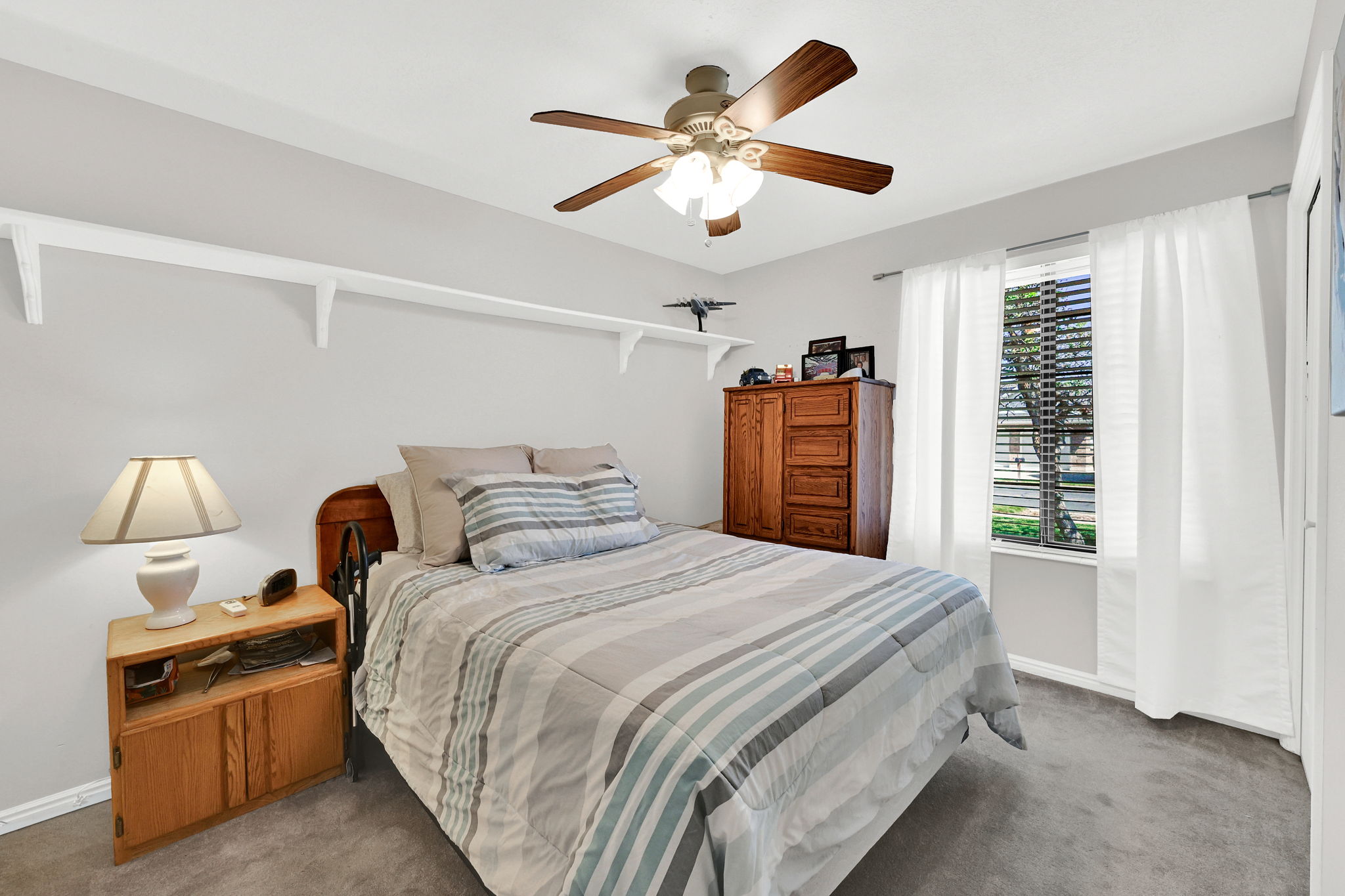 Carpeted bedroom #2 featuring a ceiling fan with integrated lighting, a window with blinds and curtain rod, and light-toned wall paint