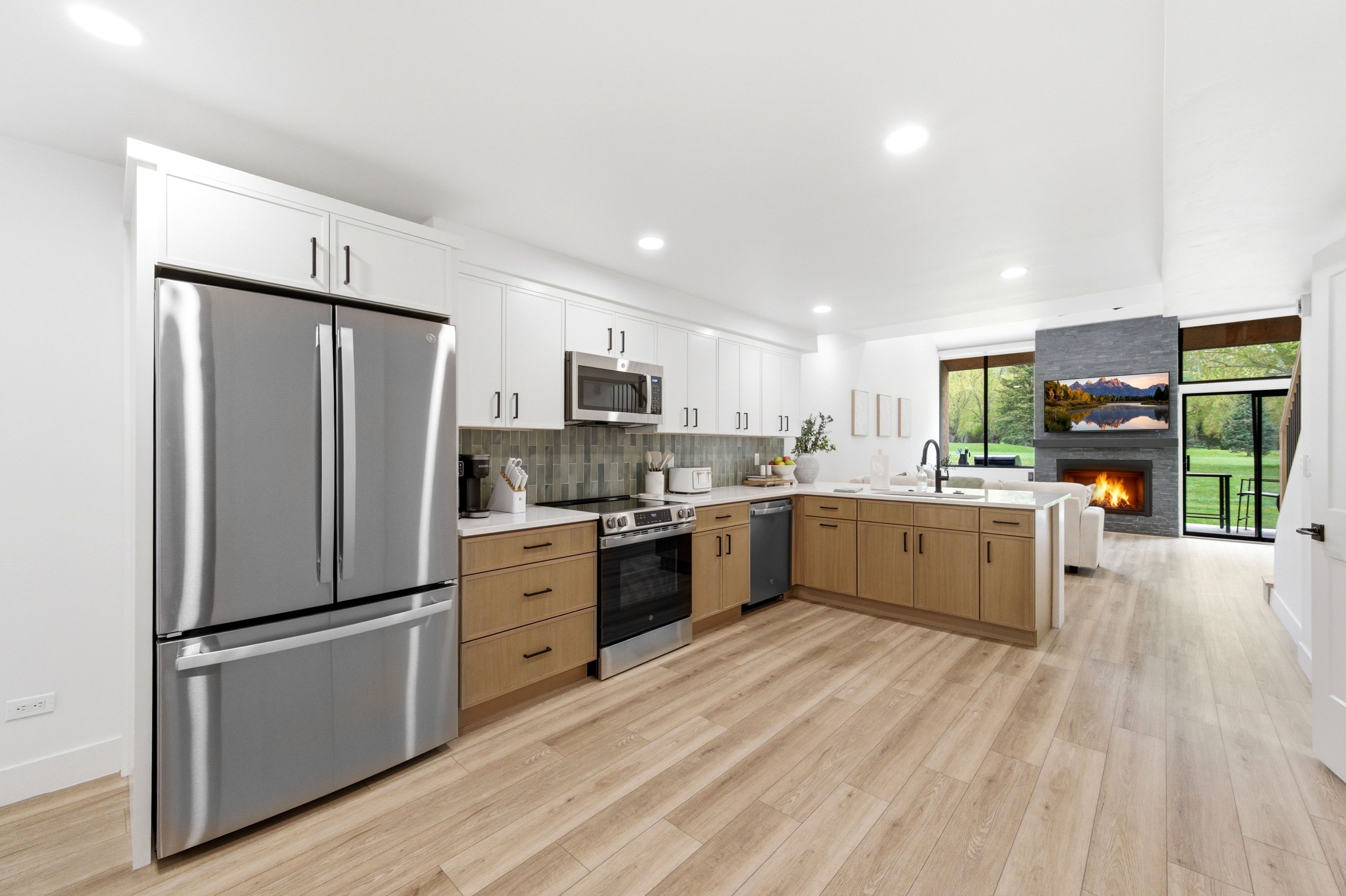 Modern kitchen featuring stainless steel appliances, two-tone cabinetry, and wood-finish flooring