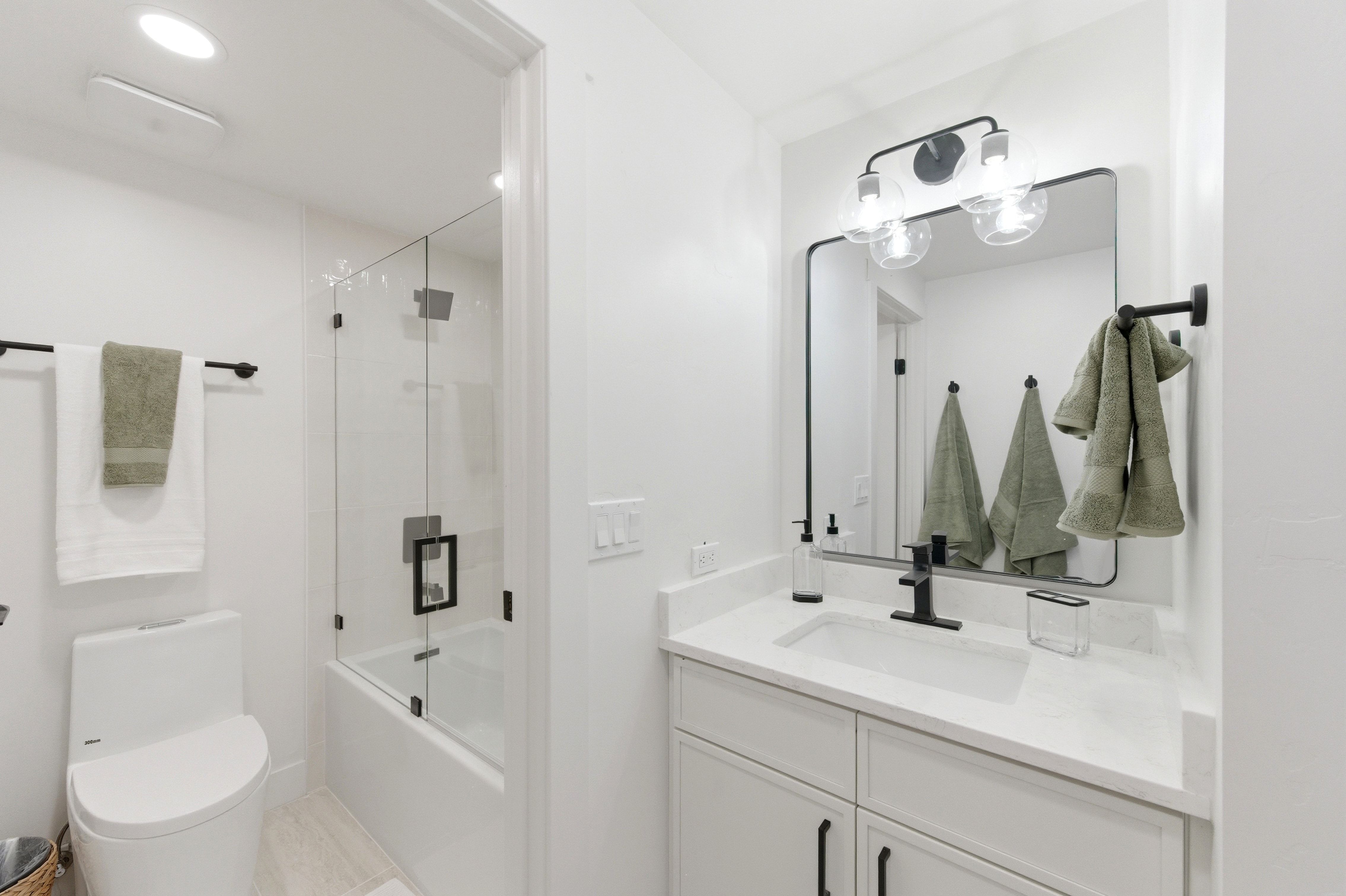 Bathroom featuring a white vanity with an undermount sink, a stone countertop, and matte black fixtures
