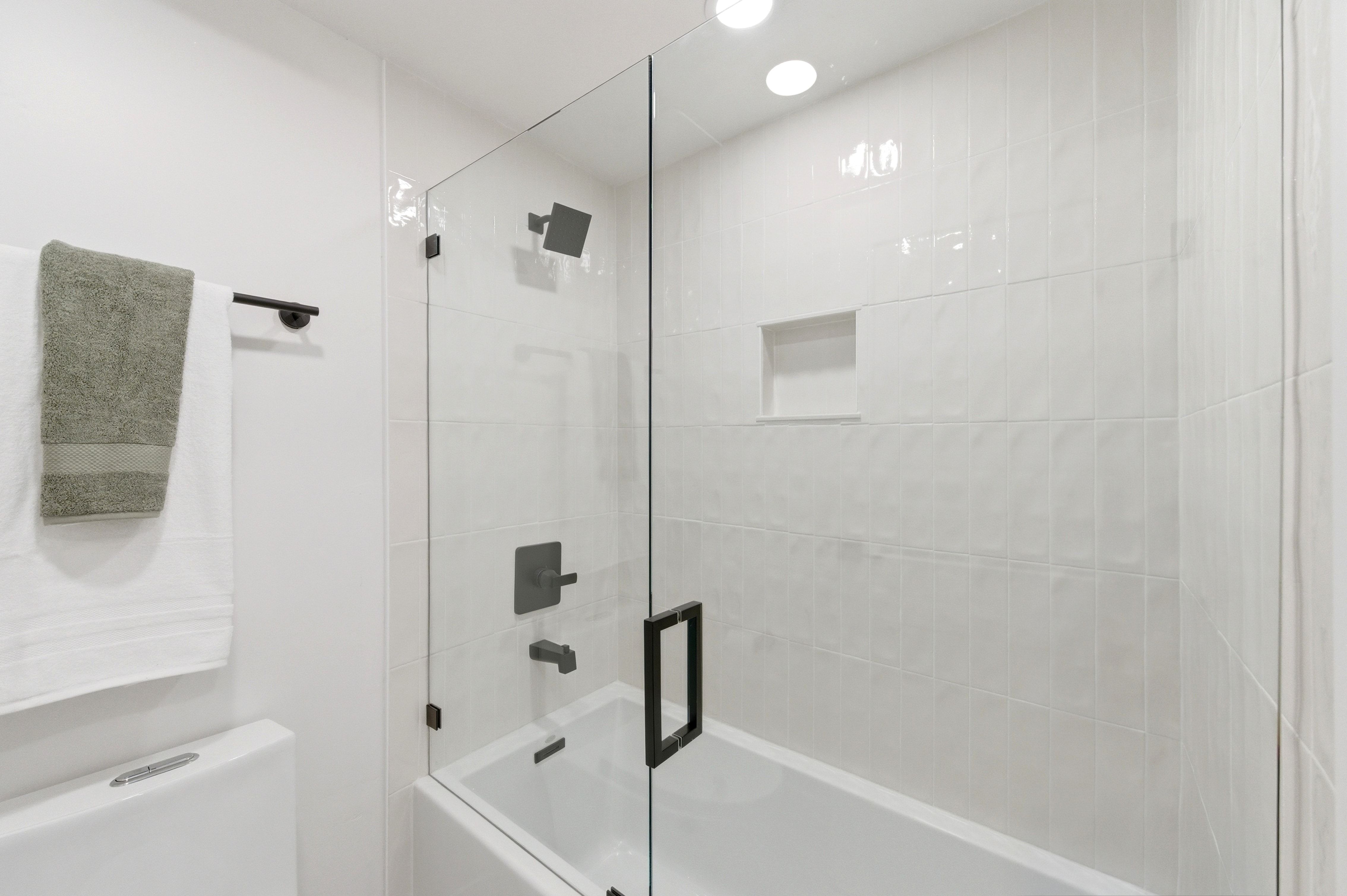 Full bathroom featuring a tub-shower combination with a frameless glass enclosure