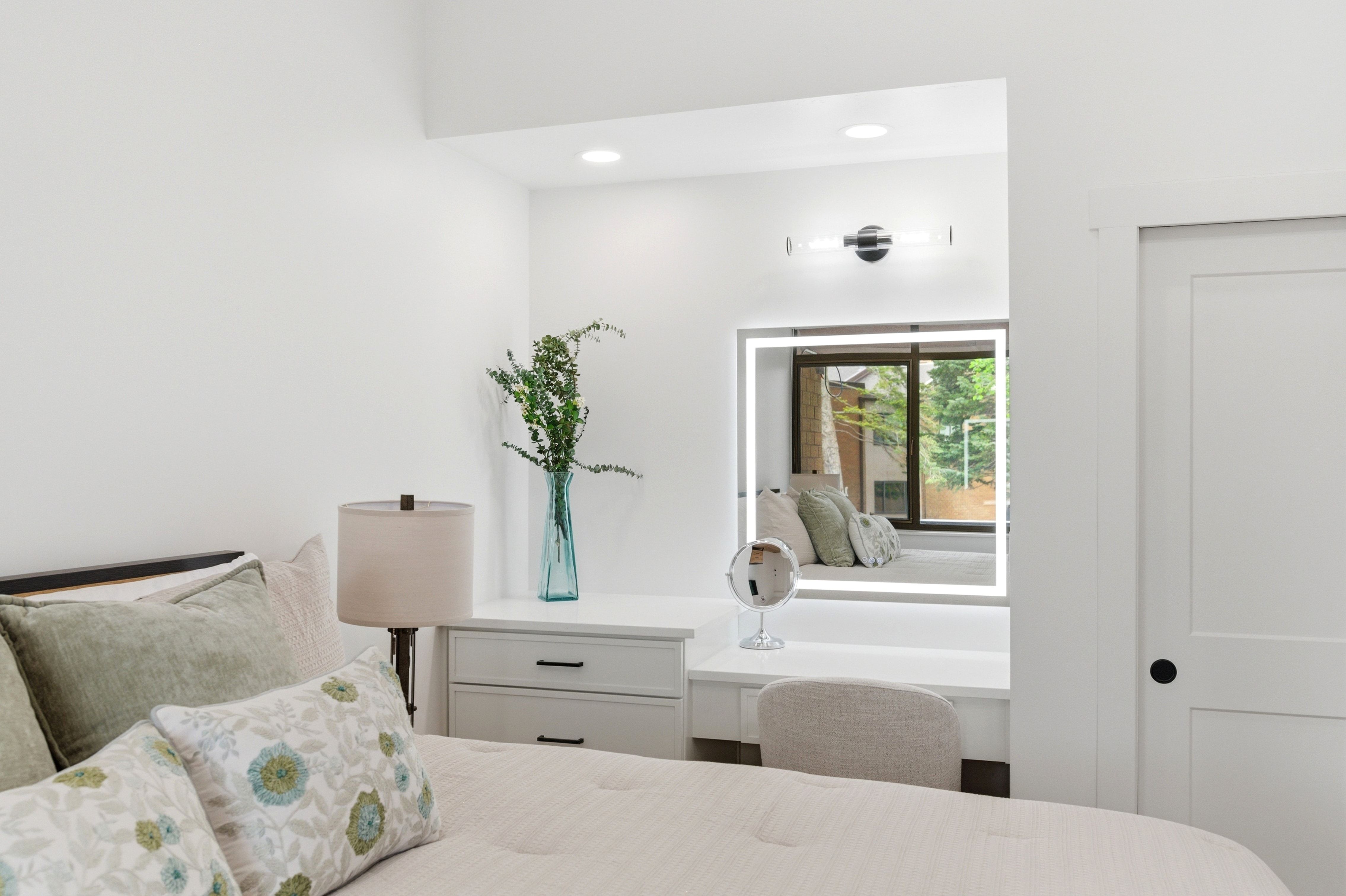 Recessed vanity area featuring a built-in illuminated mirror, dedicated task lighting, and a window seat