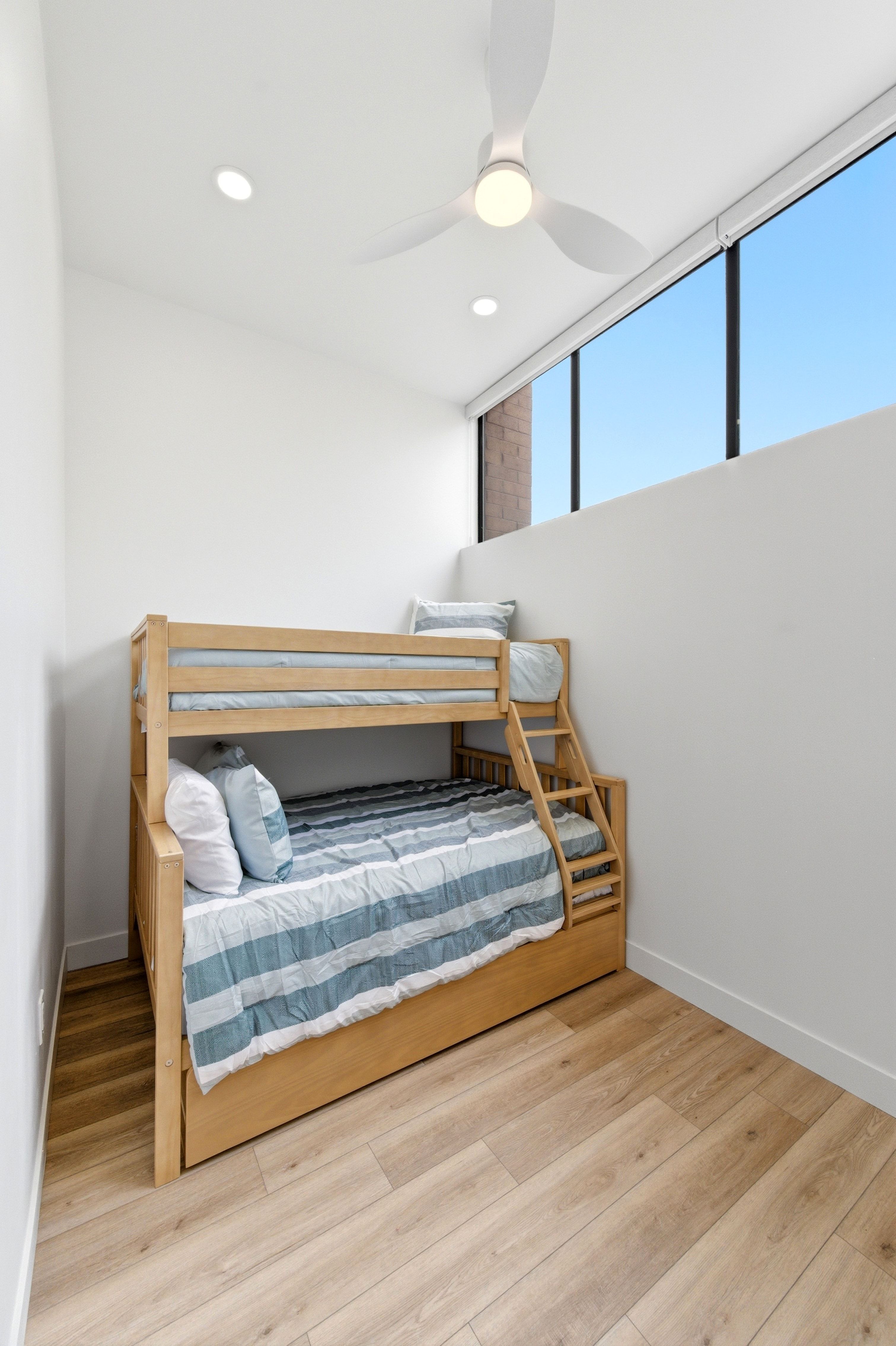 Room featuring high ceilings, wood-finish flooring, a modern ceiling fan, recessed lighting, and expansive upper windows