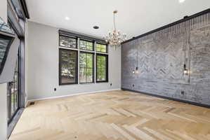 Herringbone wood-finish flooring complements a feature wall with gray brick and recessed lighting